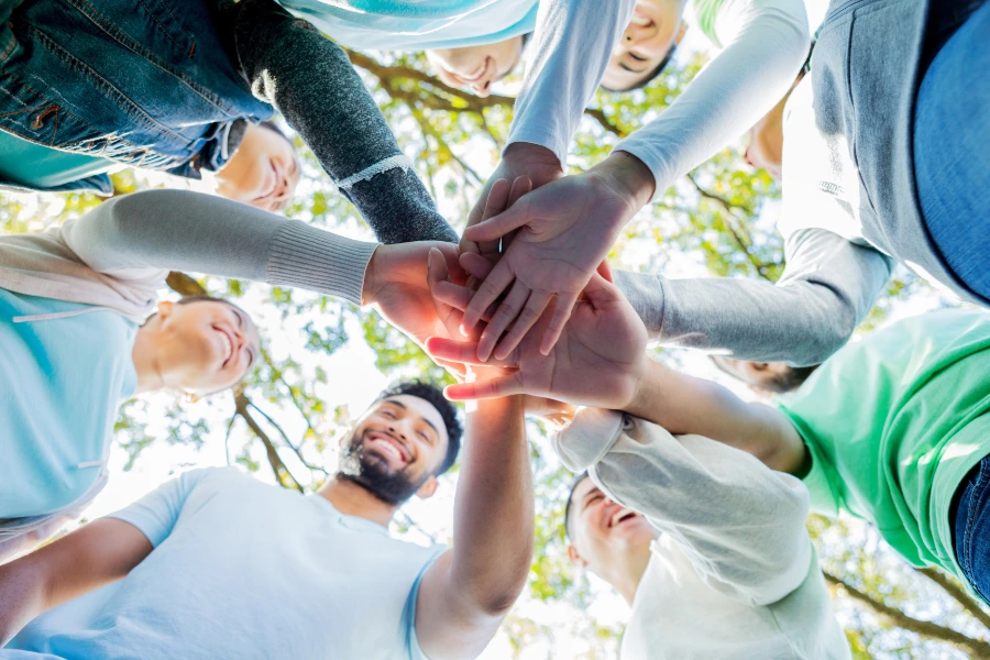 A group of people in a circle with their hands touching in the centre.